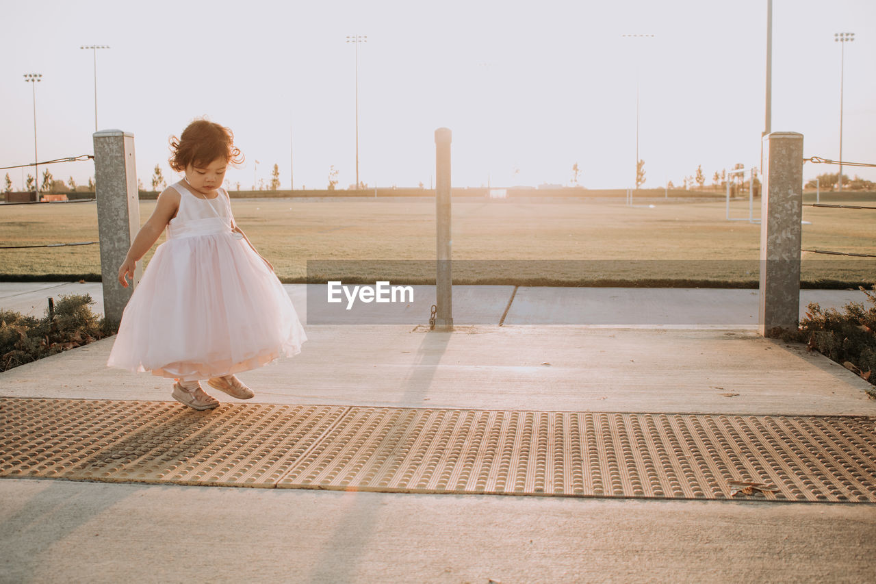 Cute baby girl looking down while standing on footpath