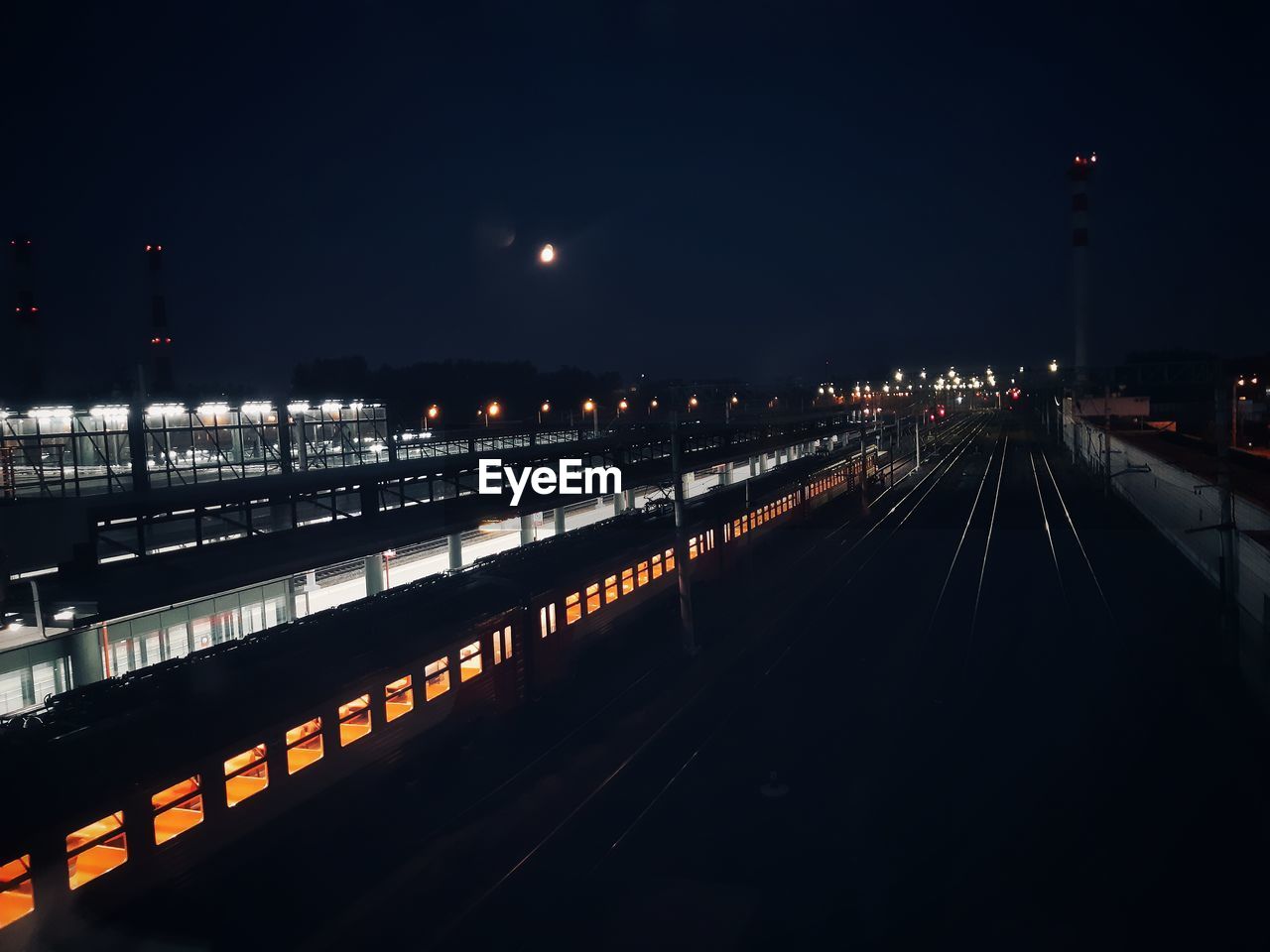 Illuminated railroad station against sky at night