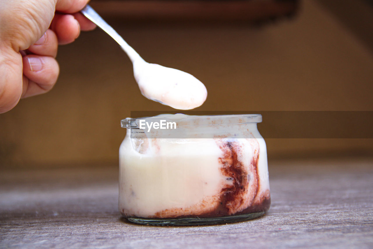 CLOSE-UP OF PERSON HAND HOLDING ICE CREAM