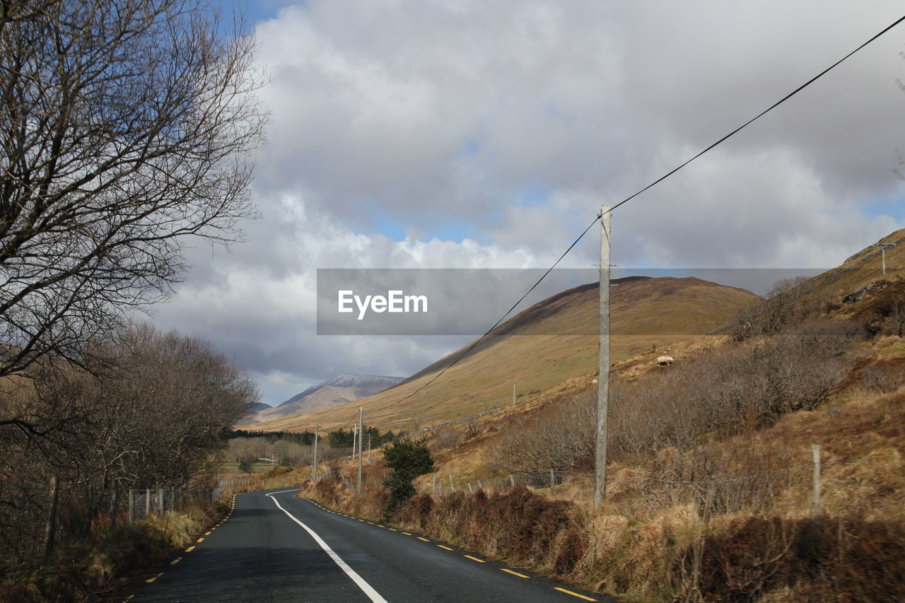 Country road amidst landscape against sky