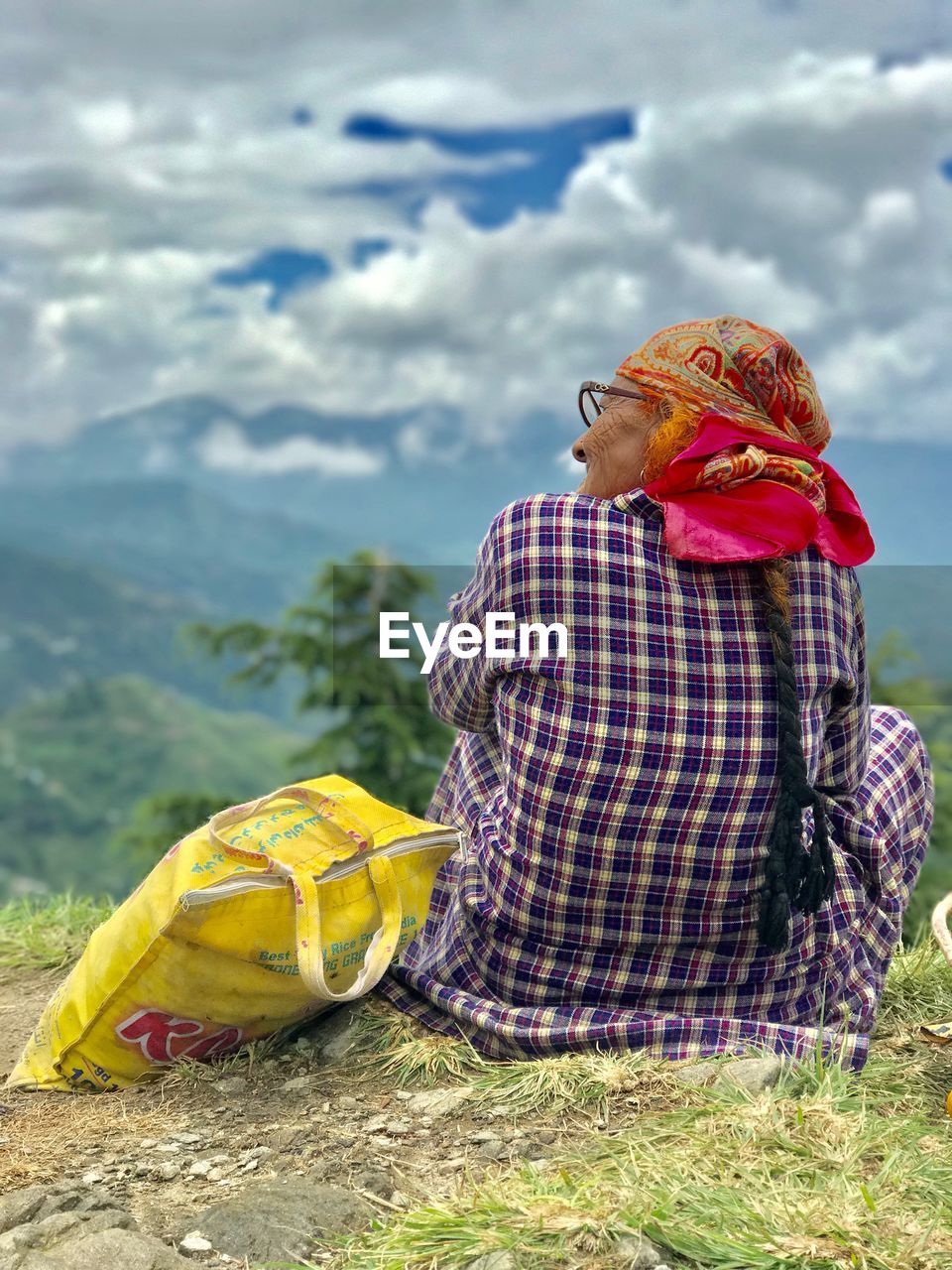 Rear view of senior woman looking at landscape while sitting on mountain