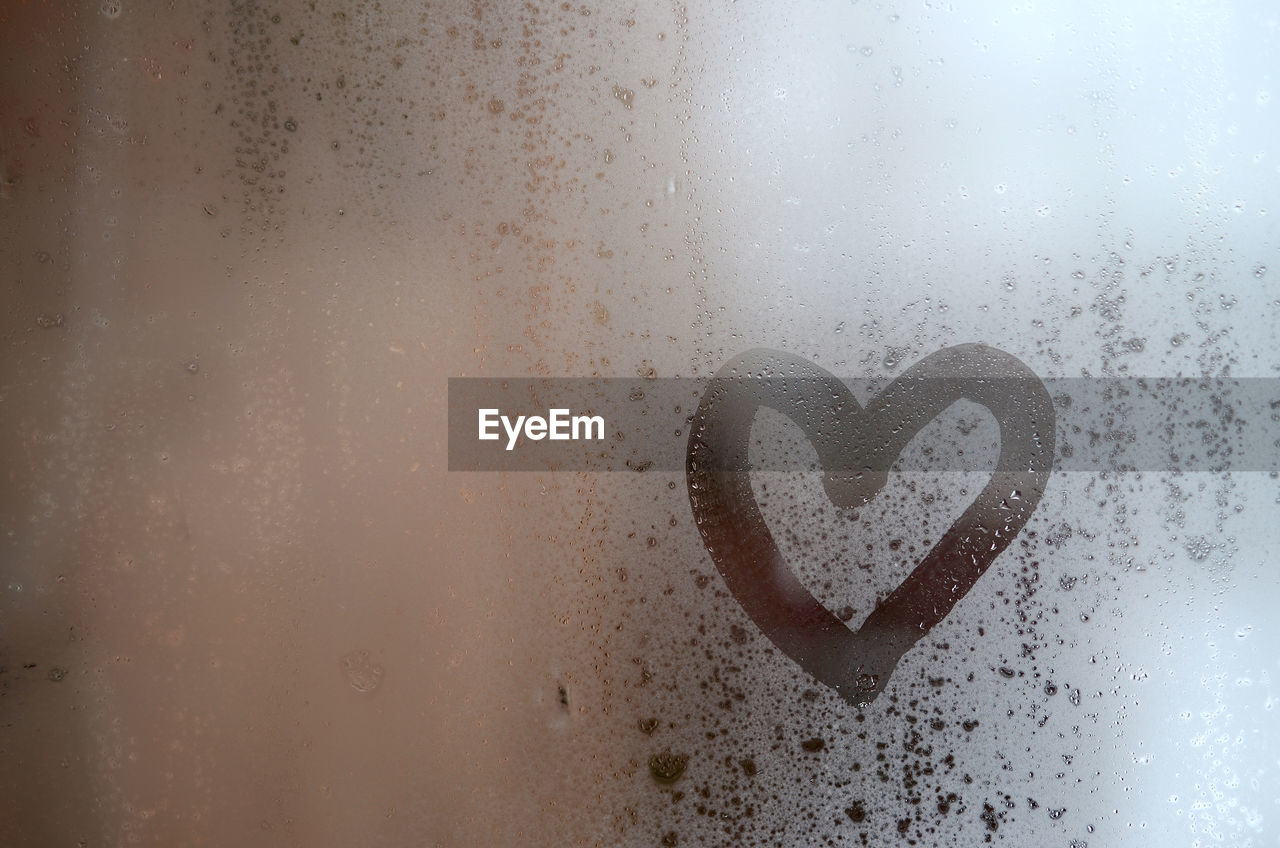 Close-up of heart shape on condensed glass window