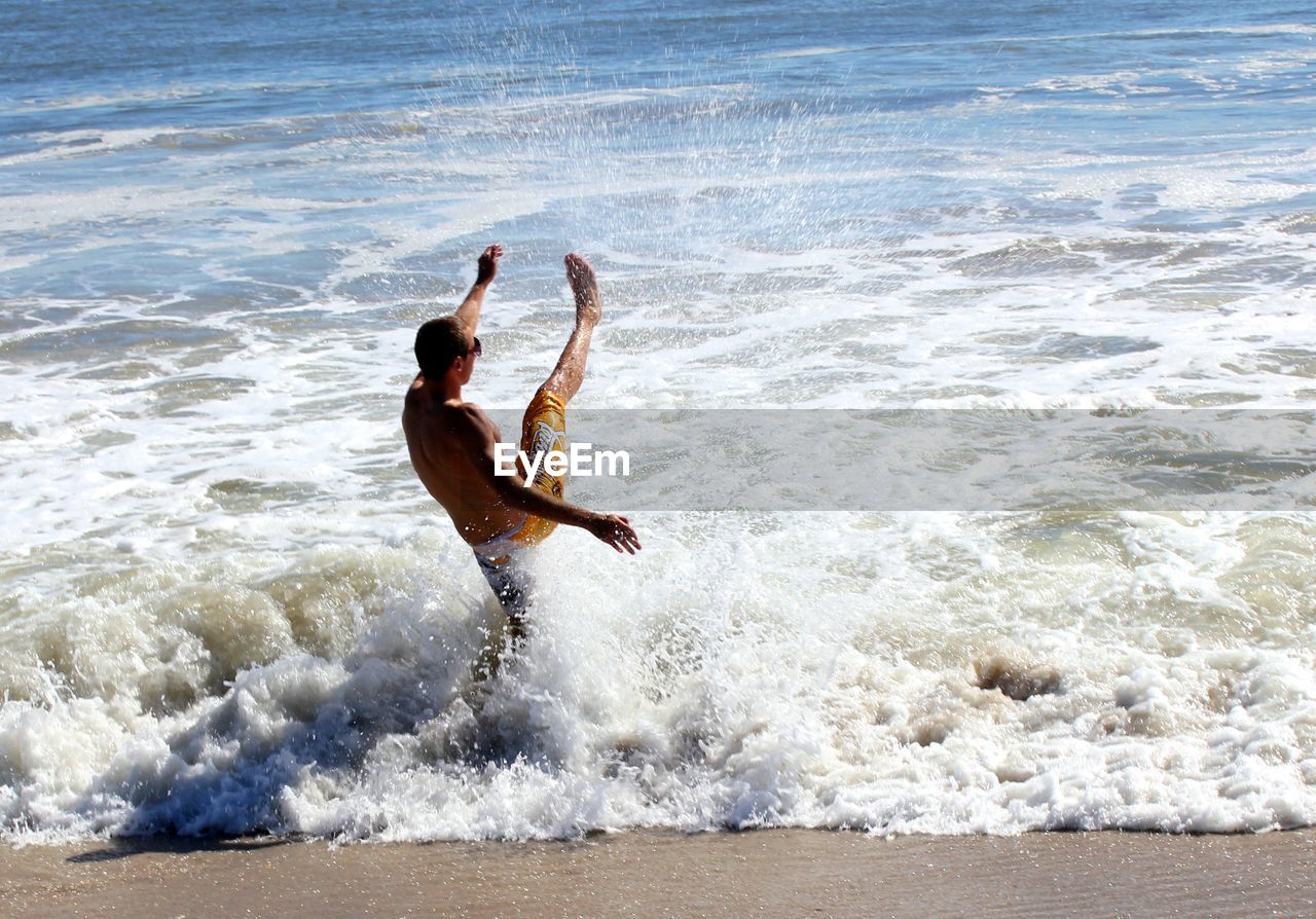 Shirtless man splashing water in sea