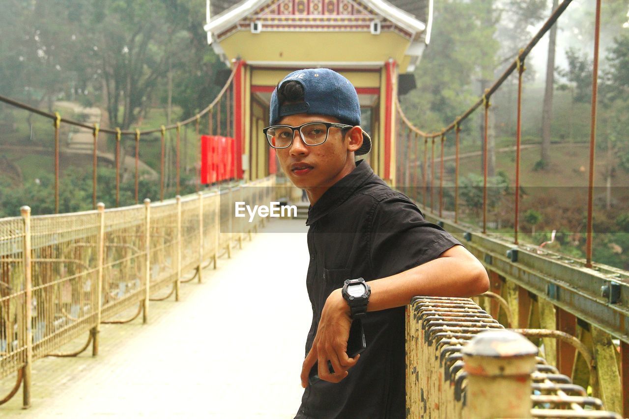 Portrait of man standing on footbridge