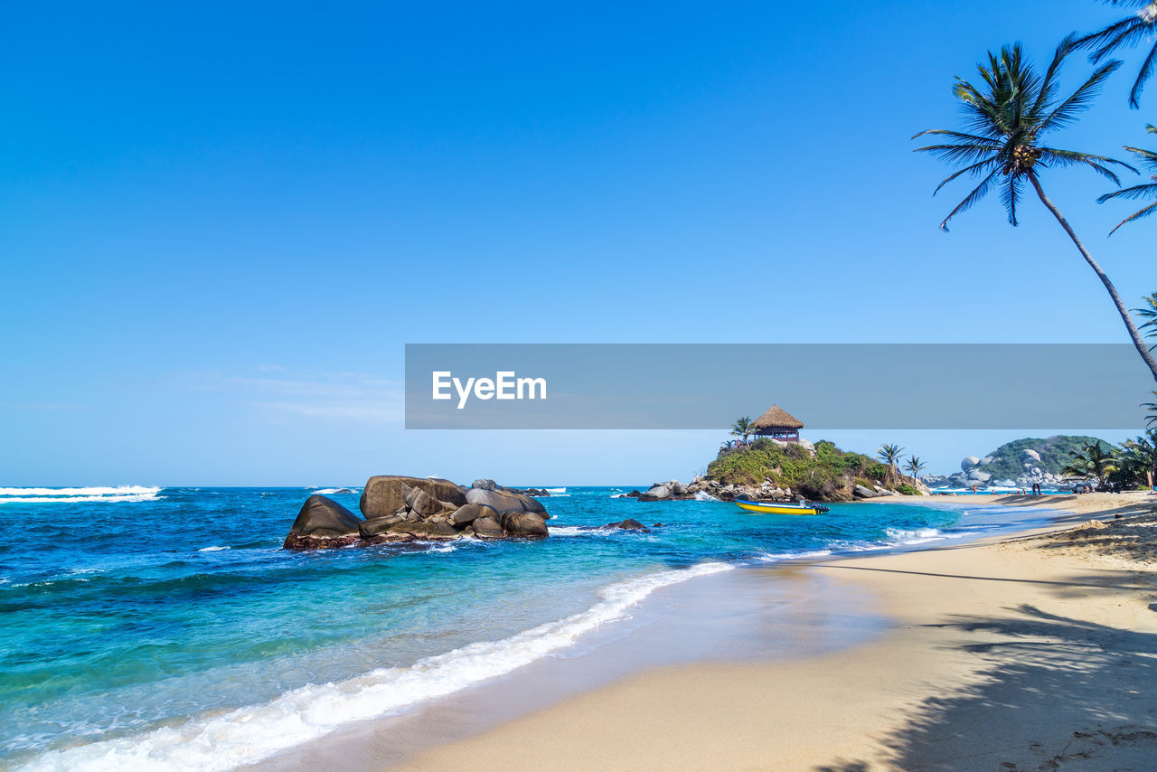 Scenic view of beach and sea against blue sky at tayrona national park
