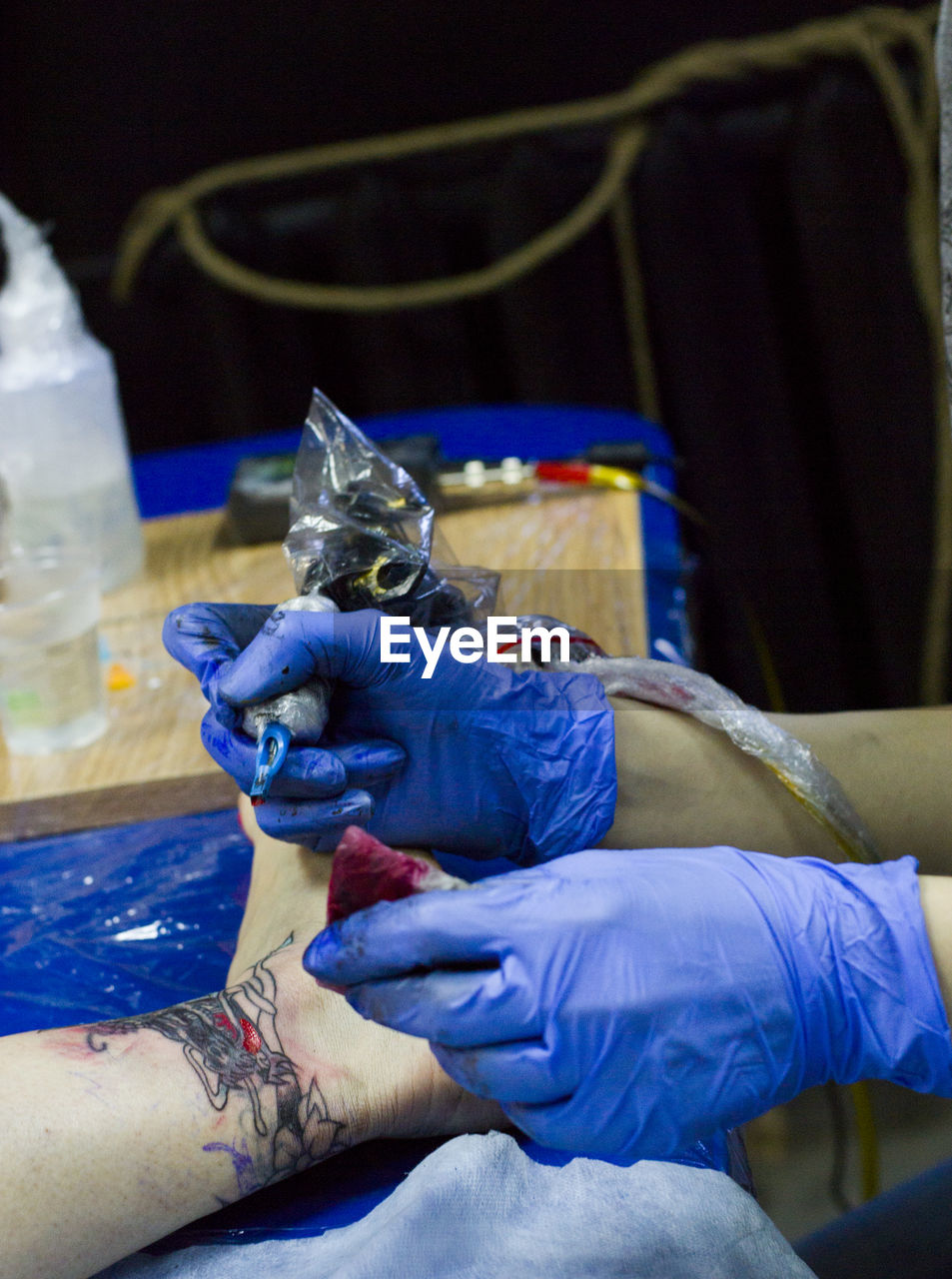 Cropped hands of tattoo artist tattooing on customer leg