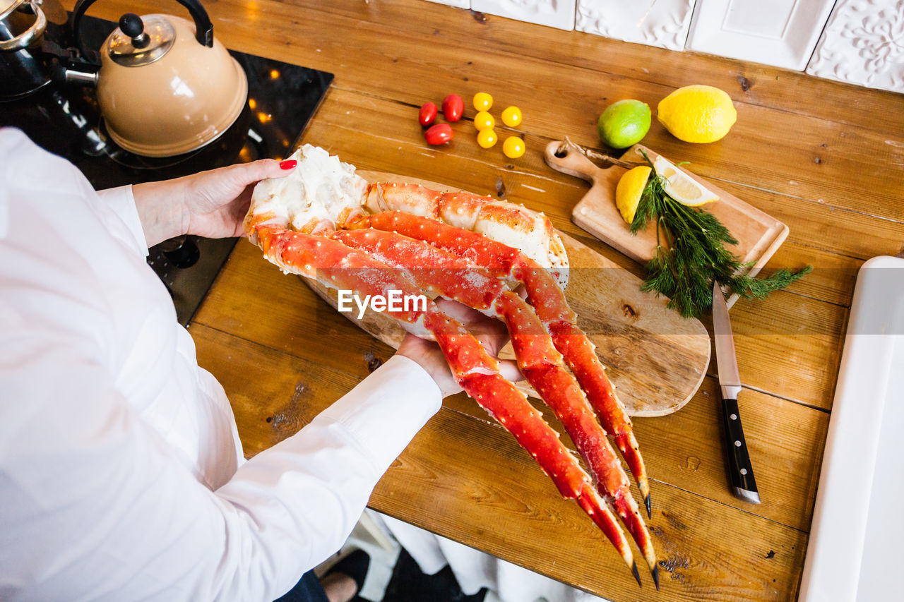 HIGH ANGLE VIEW OF MAN CUTTING BOARD IN KITCHEN