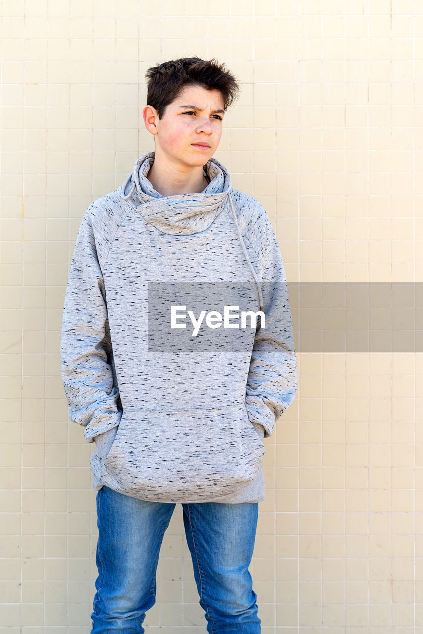 Portrait of a teenage boy looking away against yellow wall