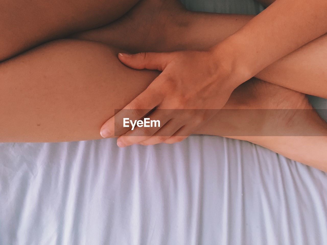 Midsection of woman sitting on bed at home