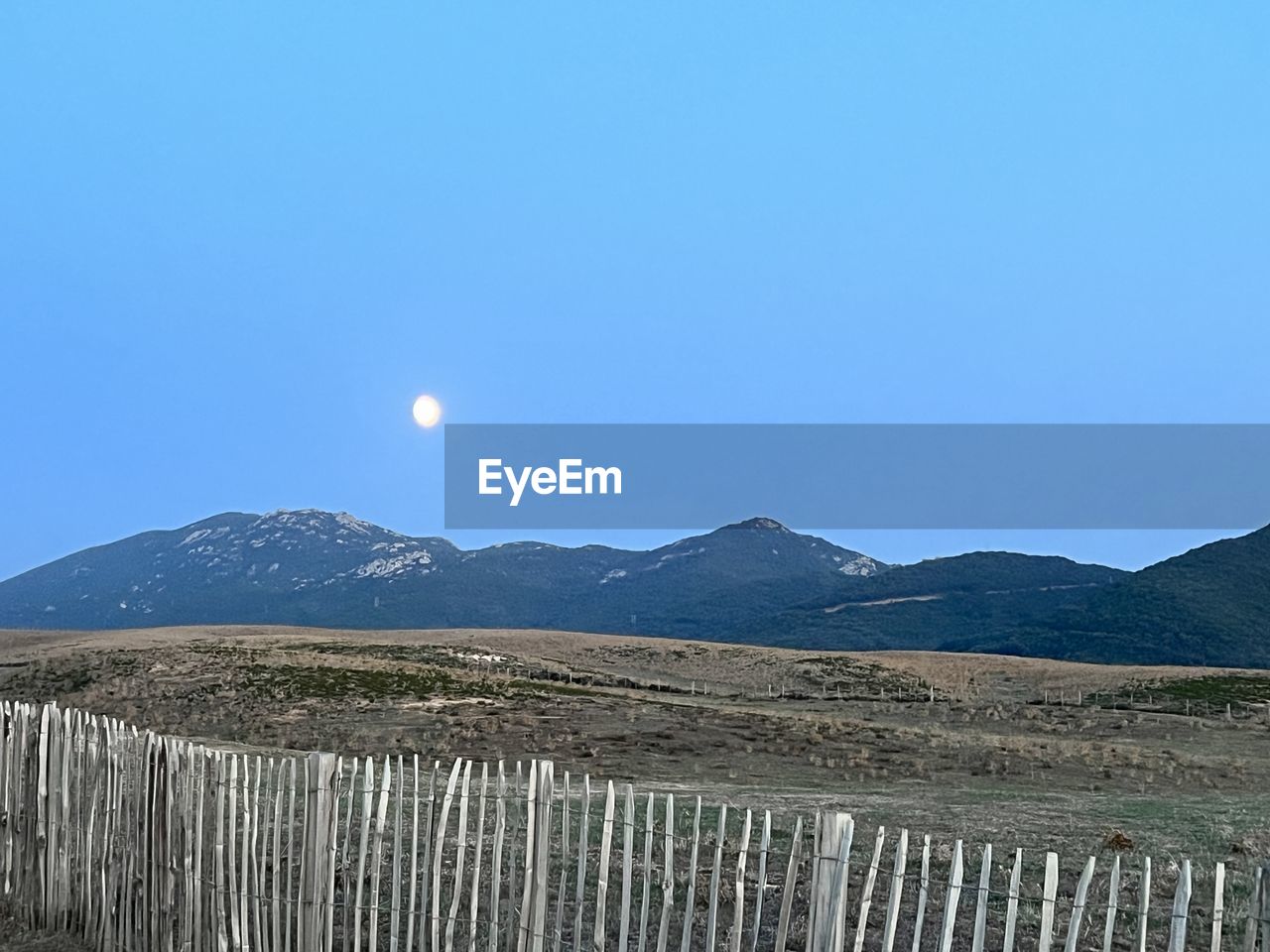 sky, mountain, scenics - nature, landscape, environment, nature, moon, no people, beauty in nature, land, tranquil scene, tranquility, blue, clear sky, mountain range, horizon, outdoors, fence, non-urban scene, day, full moon, sunny, copy space, travel, travel destinations