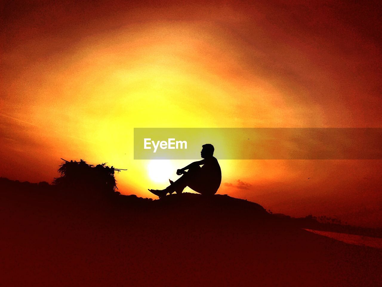 Silhouette of person sitting on rock