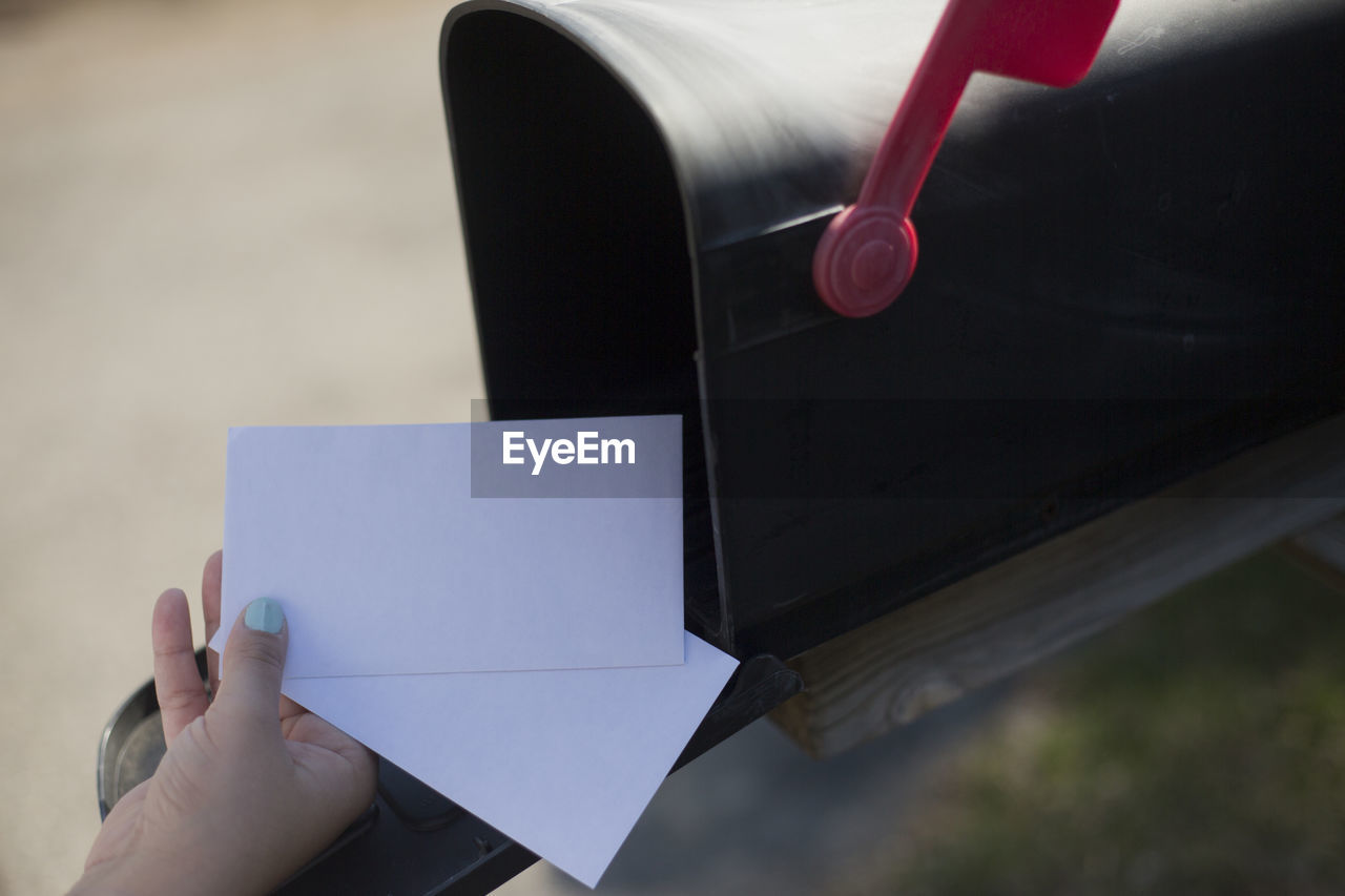 Cropped image of woman removing letter from mailbox