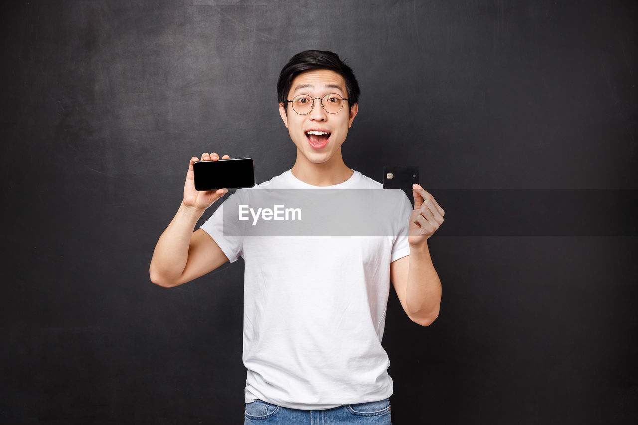 Man with credit card and smart phone against black background