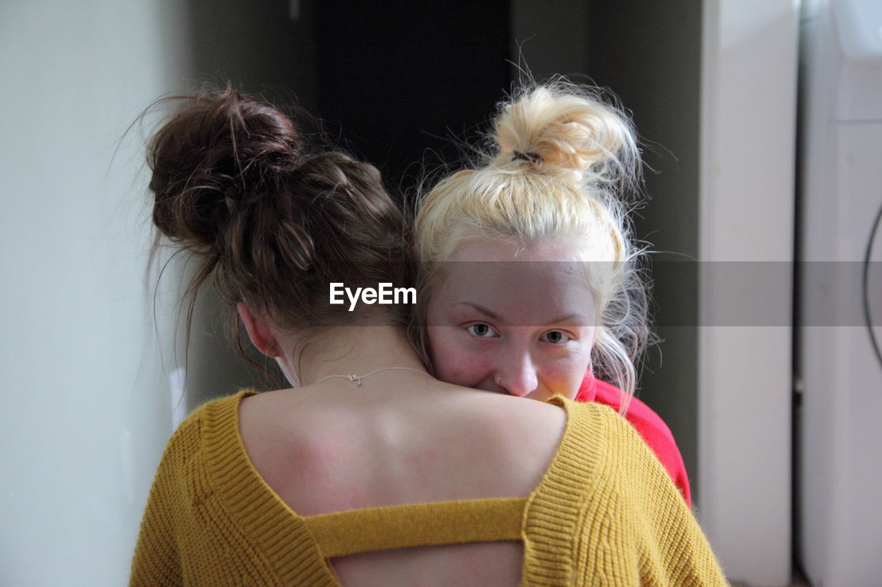 Portrait of smiling lesbian woman embracing girlfriend at home