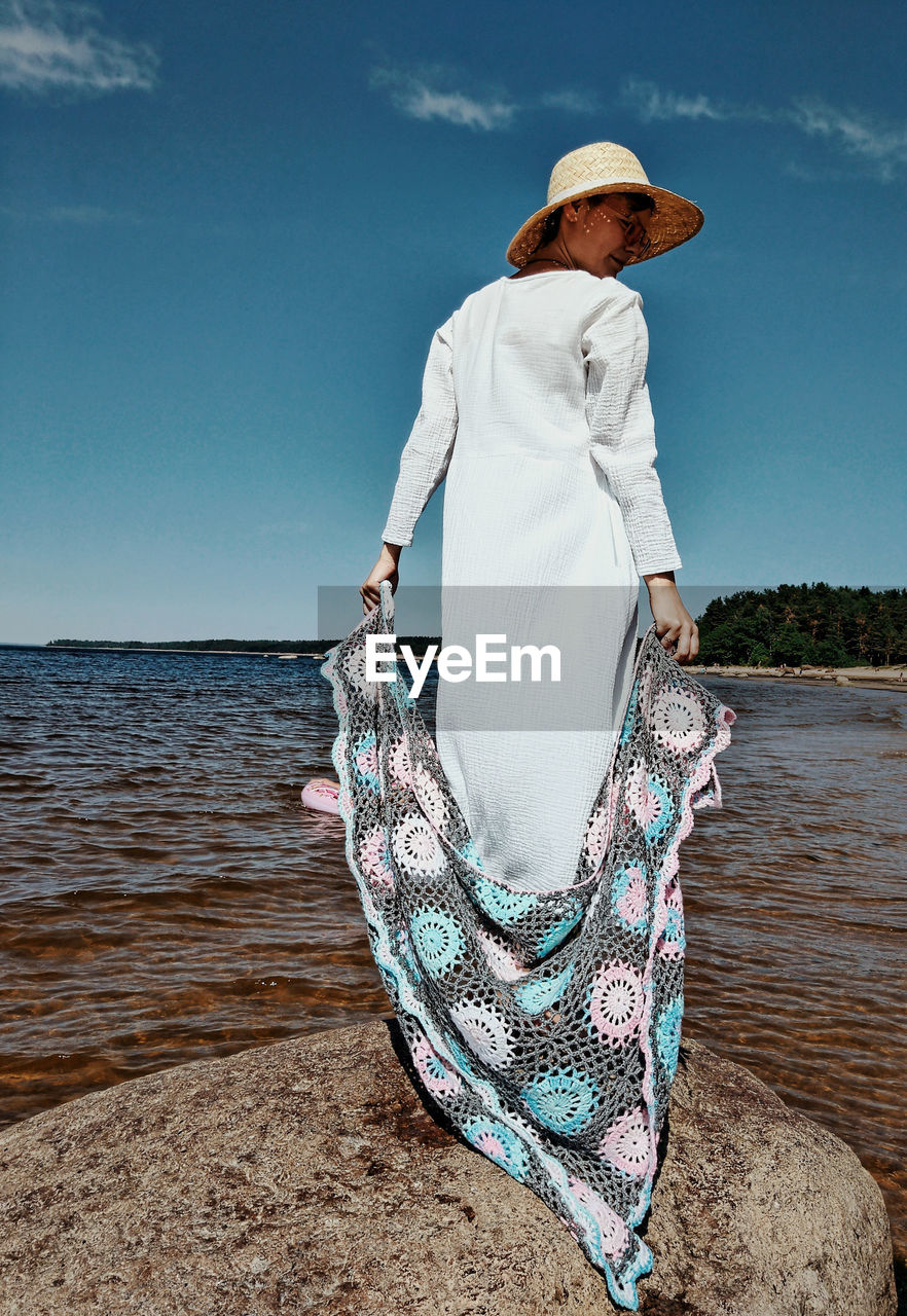 Rear view of woman standing by sea against sky