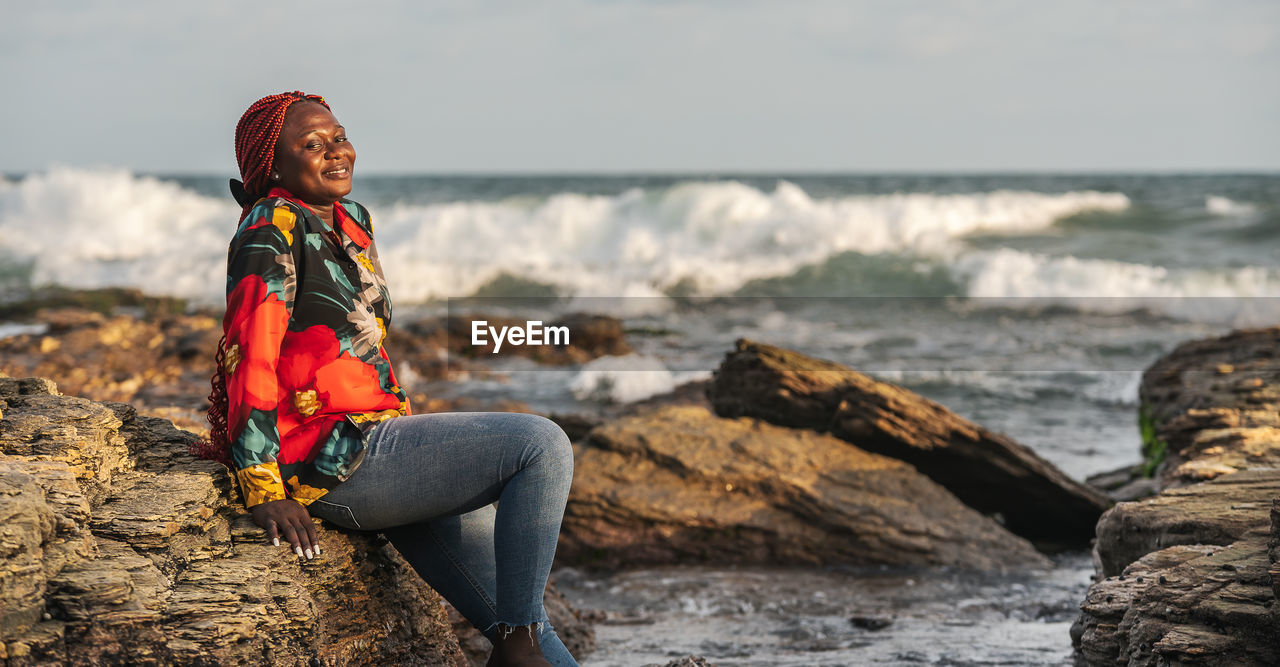 African woman sitting on the beach cliffs at sunset in accra ghana west africa