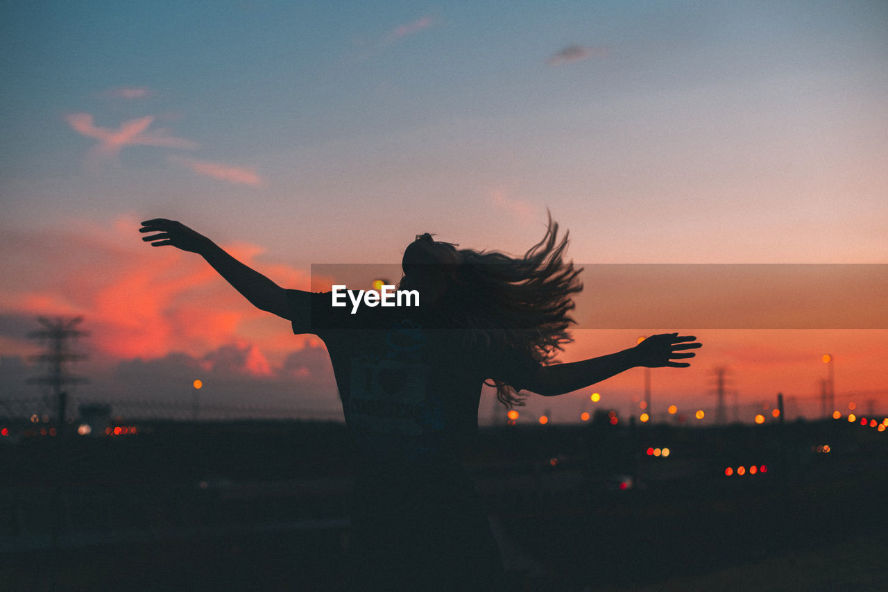 Front view of a woman with arms outstretched blue hour