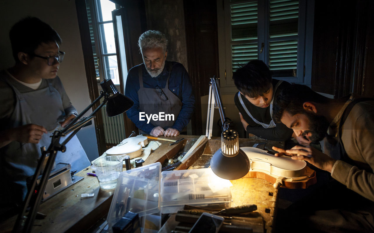 Group of craftsmen violin maker while working on a new violin in the workshop