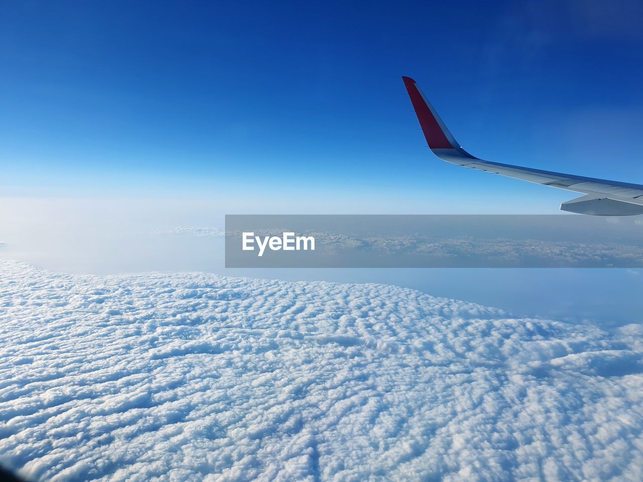 AIRPLANE FLYING OVER SNOWCAPPED MOUNTAINS AGAINST BLUE SKY