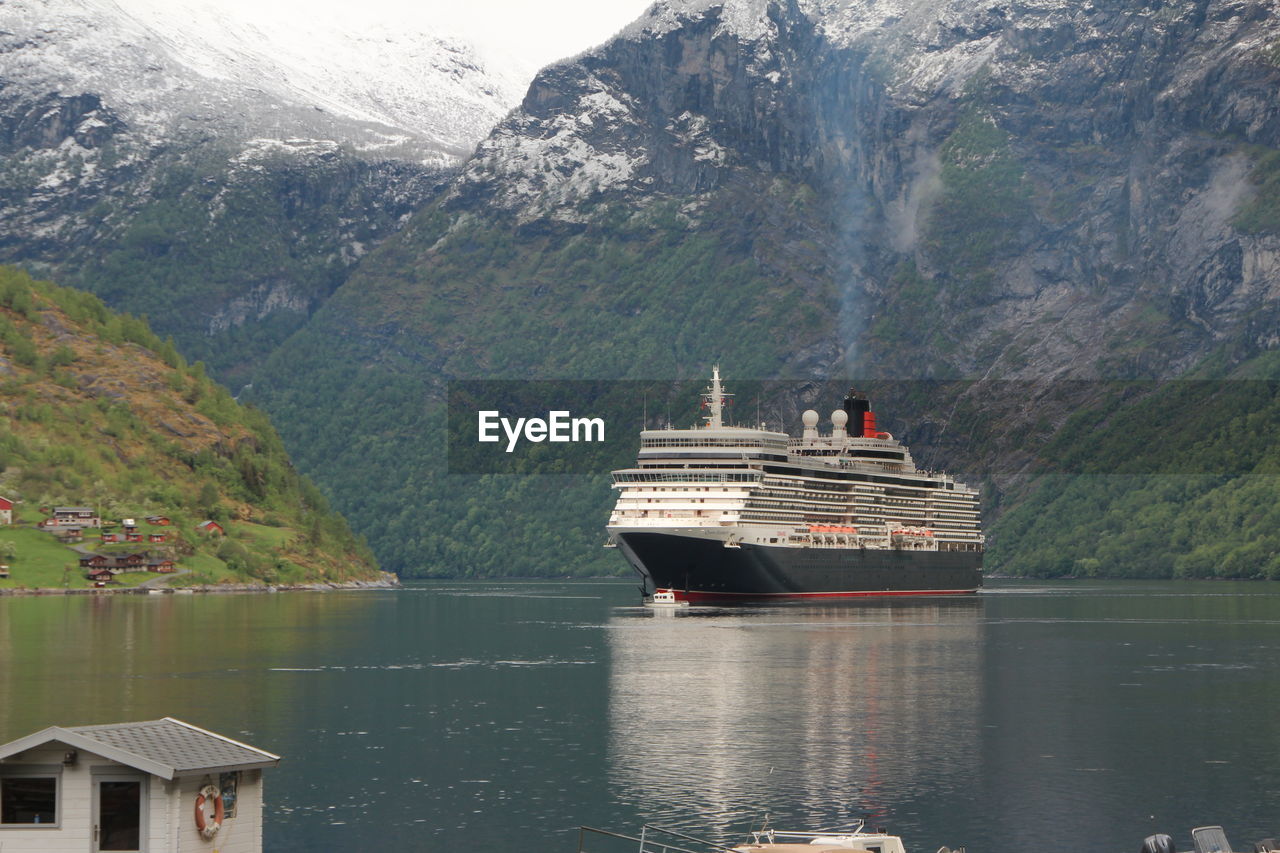 BOAT SAILING ON SEA AGAINST MOUNTAIN