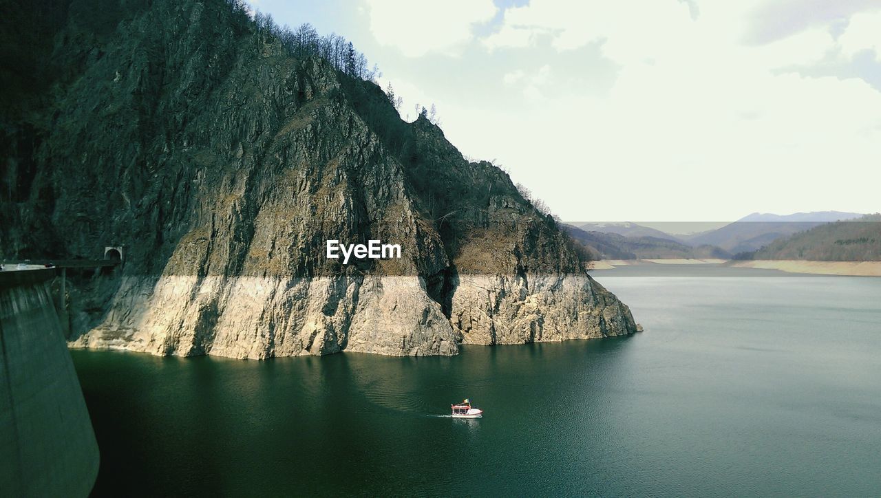 Boat on sea by mountain against sky