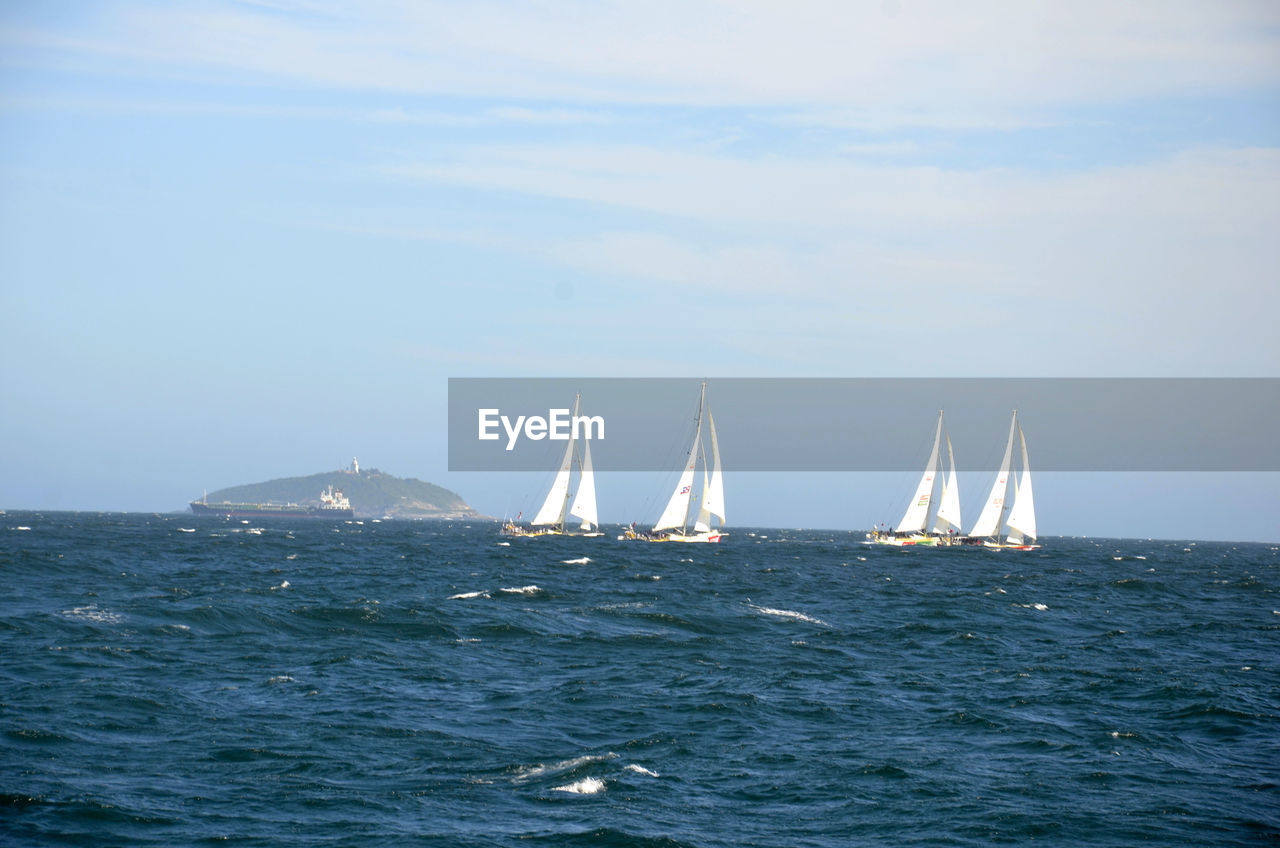 Sailboats sailing in sea against sky