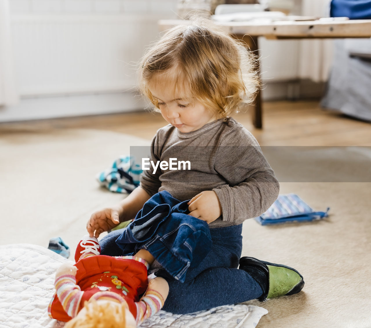 Girl playing with doll while sitting at home