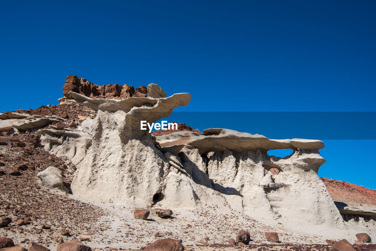 Bisti badlands landscape of dramatic grey hoodoos or caprock formations against blue sky 