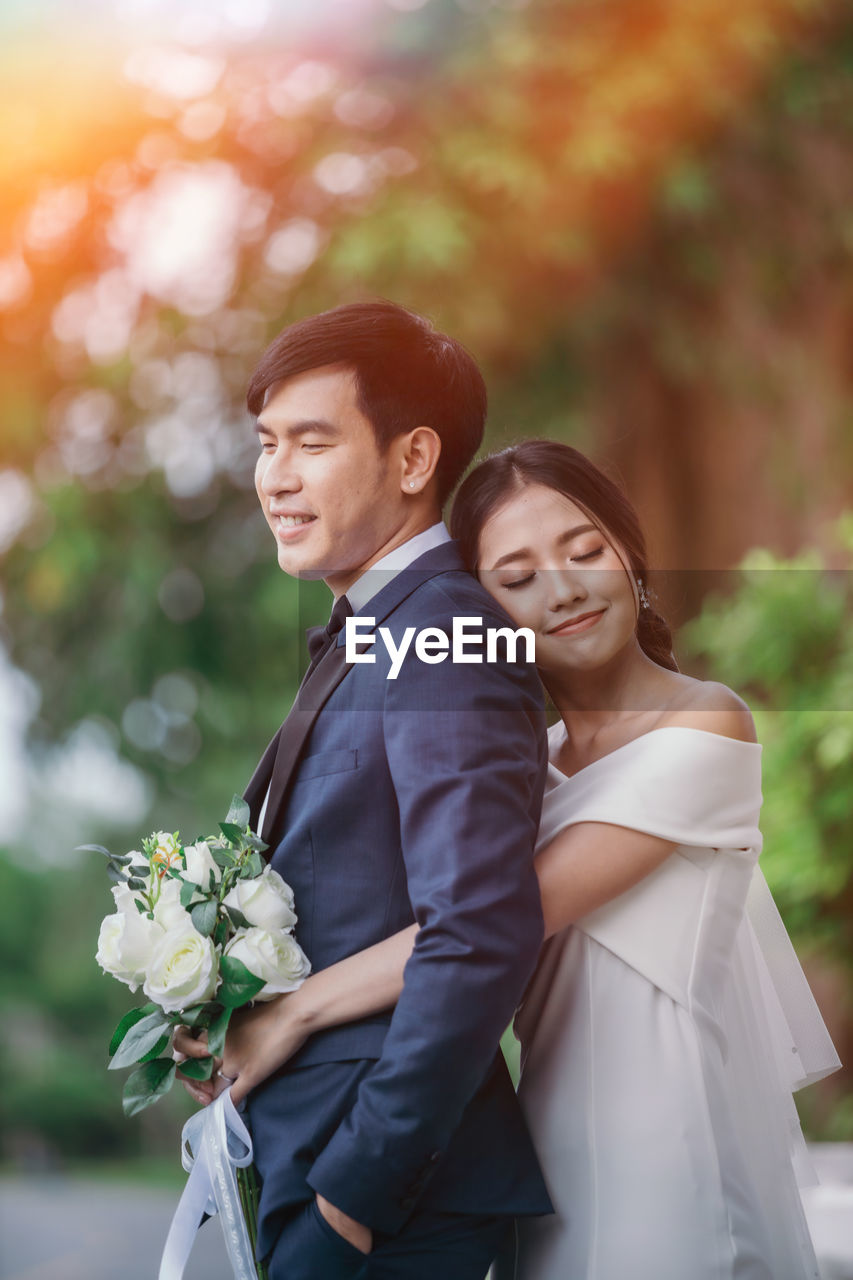 Side view of smiling couple standing by road