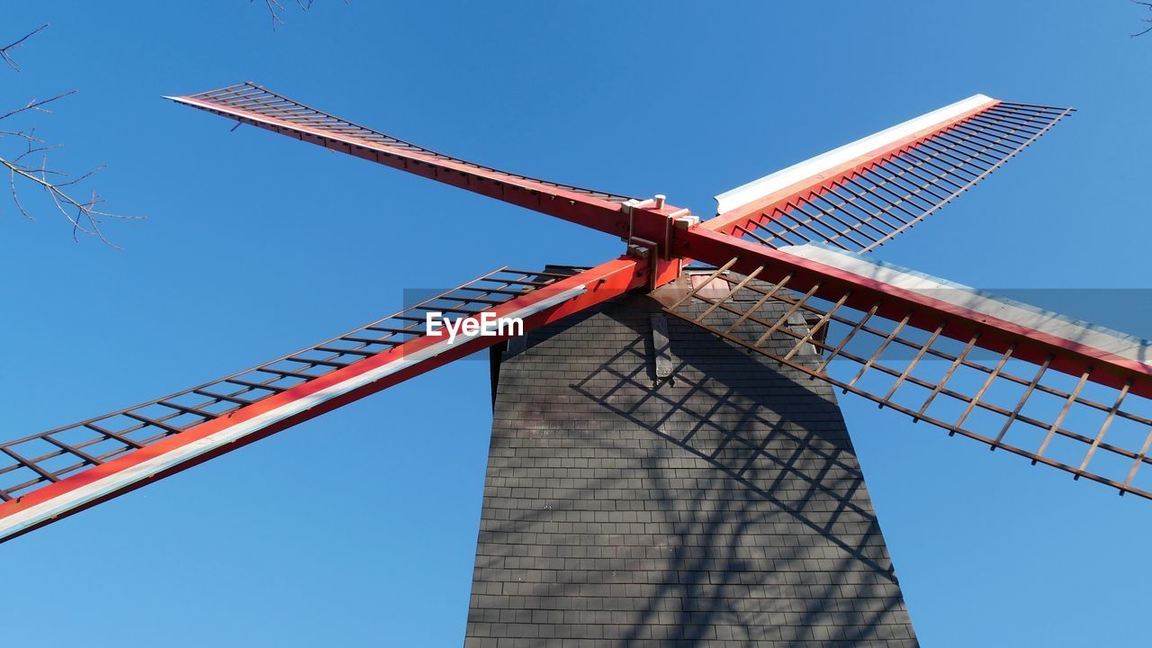 Low angle view of traditional windmill against blue sky in brugge