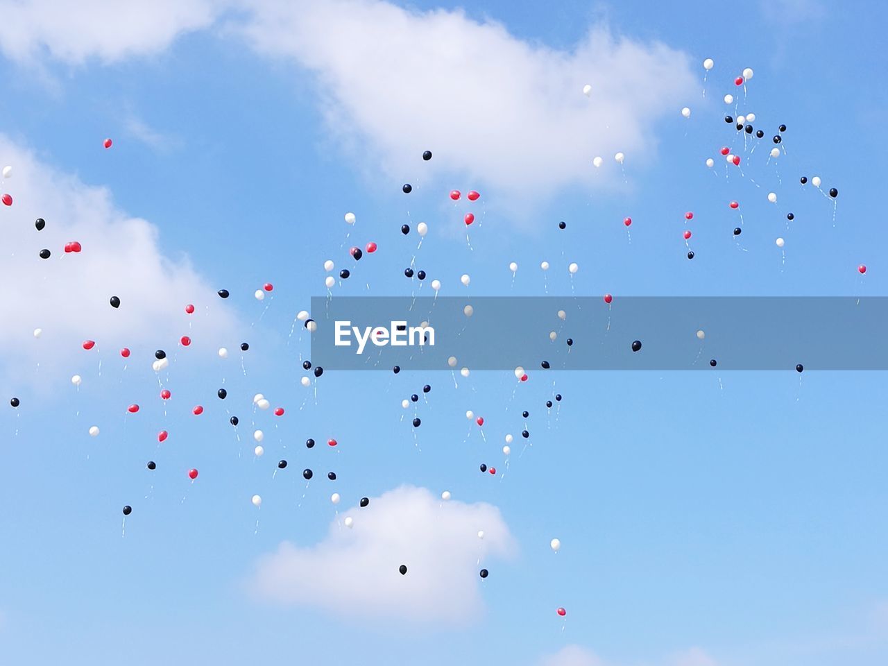 Low angle view of balloons flying against blue sky