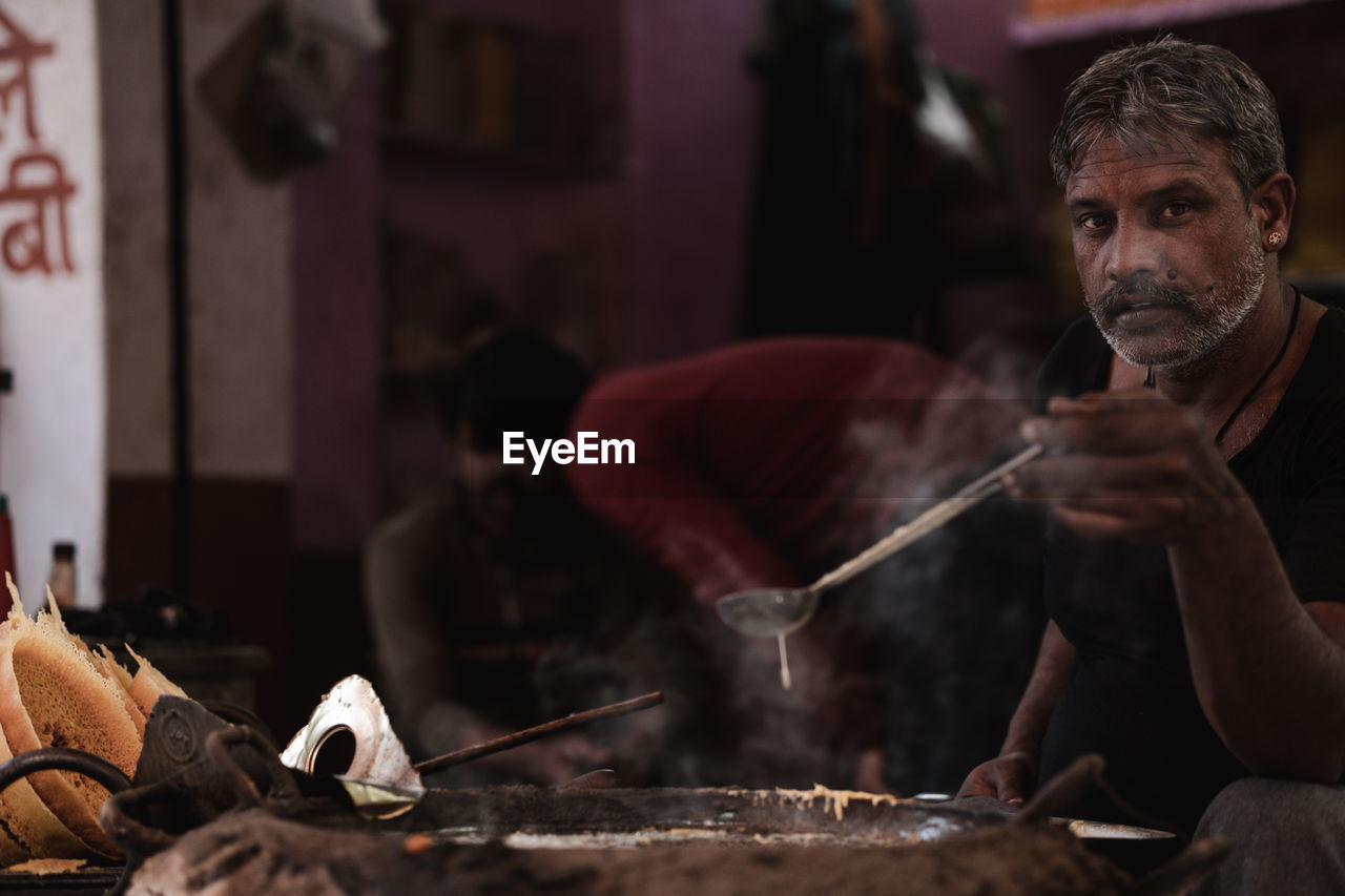 PORTRAIT OF MAN WORKING AT KITCHEN