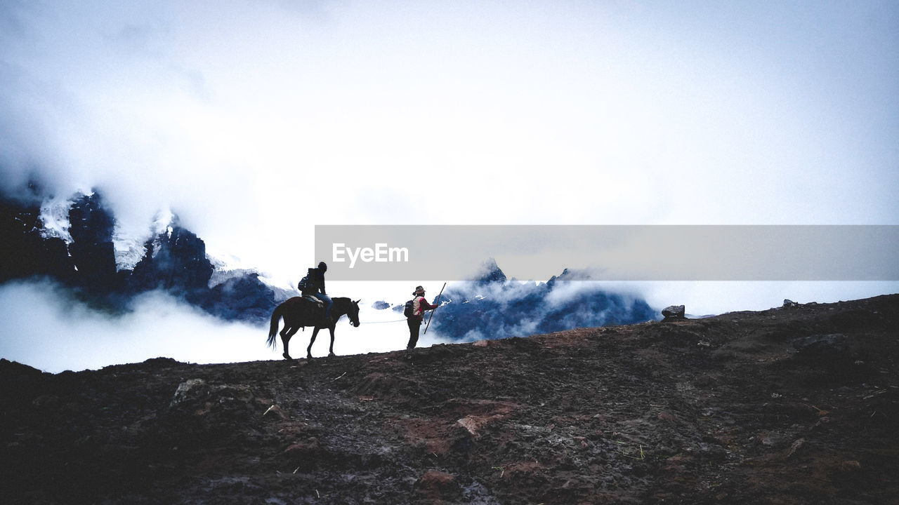 People riding horses on land against sky