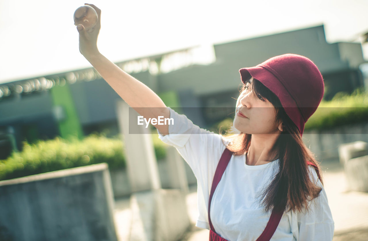 Young woman looking at crystal ball while standing outdoors