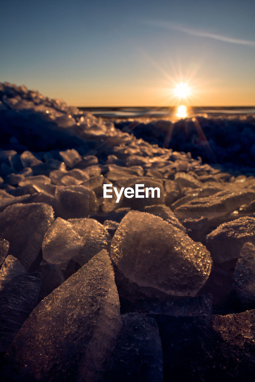 Close-up of frozen sea against sky during sunset