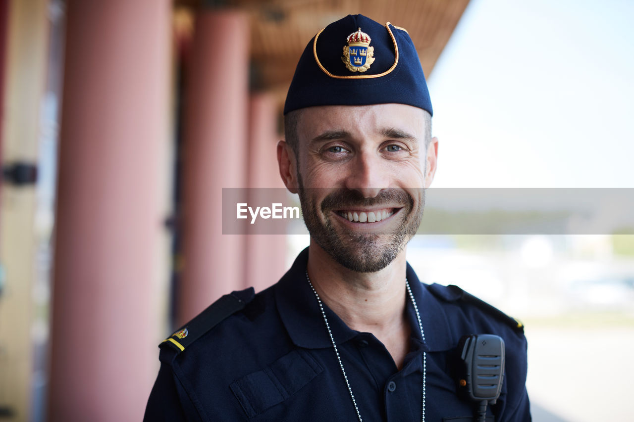 Portrait of smiling policeman standing outside police station