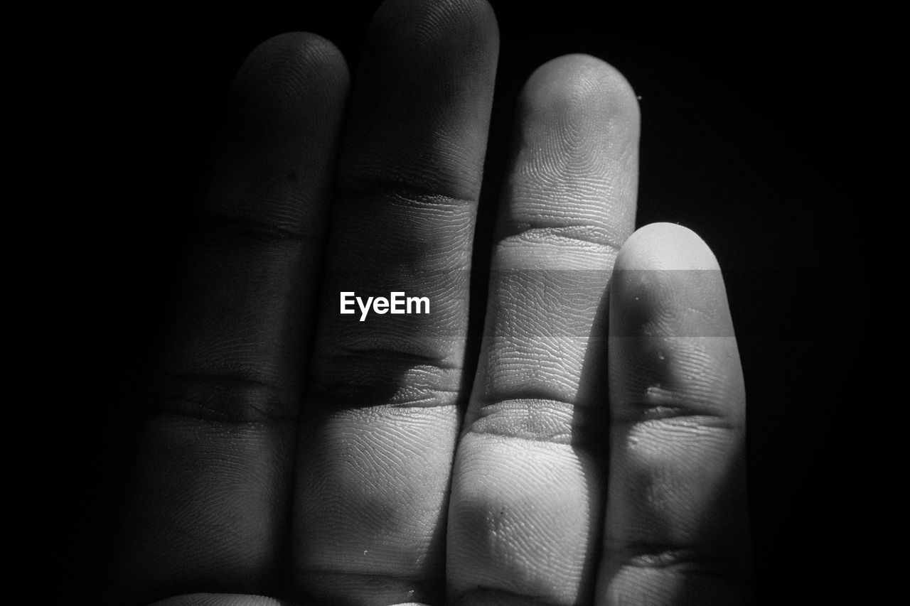 Close-up of human hand against black background