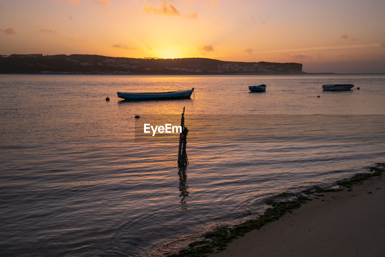 Fishing boats on a river sea at sunset in foz do arelho, portugal