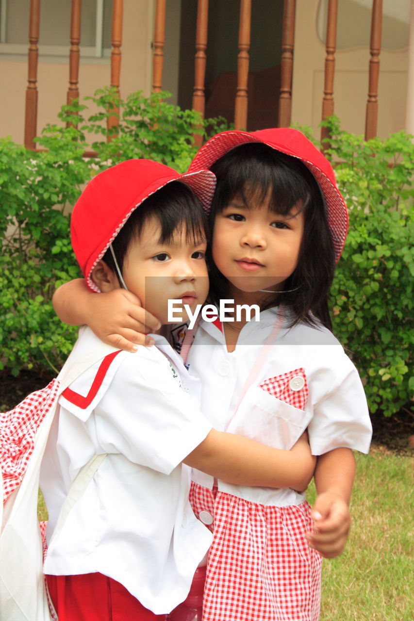 Portrait of girl embracing brother in yard