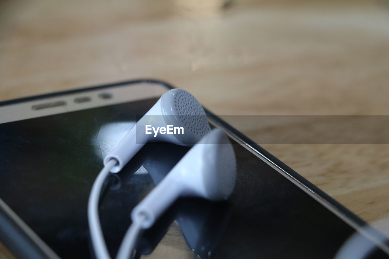 Close-up of in-ear headphones on smart phone