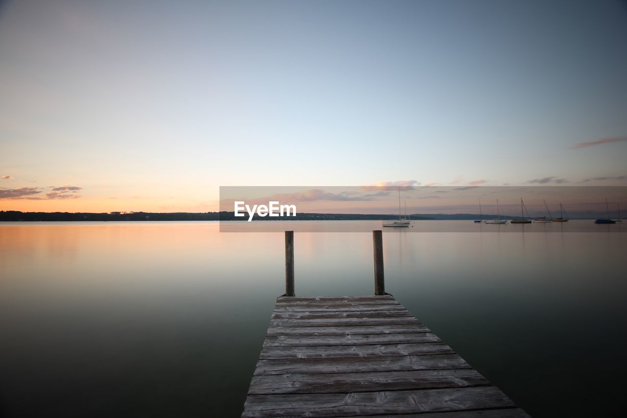 Pier over lake against sky during sunset