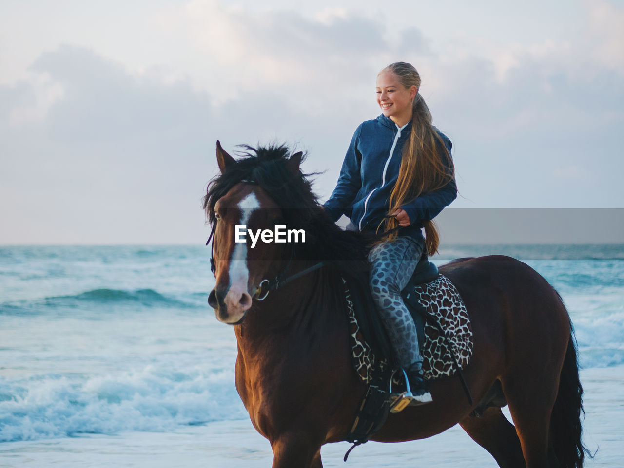 Young woman horseback riding at beach
