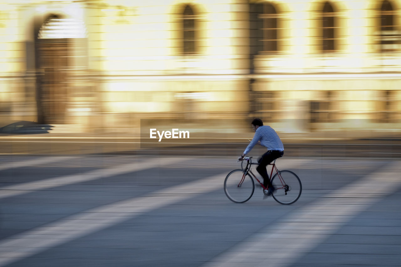 Blurred motion of man riding bicycle on street