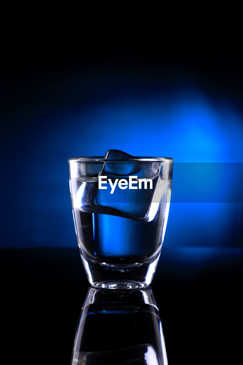 Close-up of glass on table against blue background