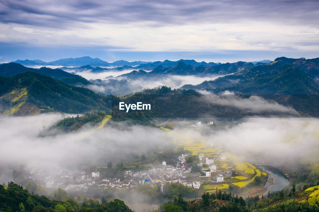 Scenic view of clouds touching mountains