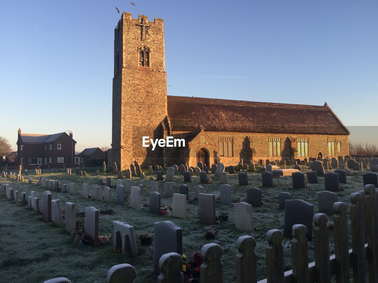 Tombstones in cemetery by church against sky