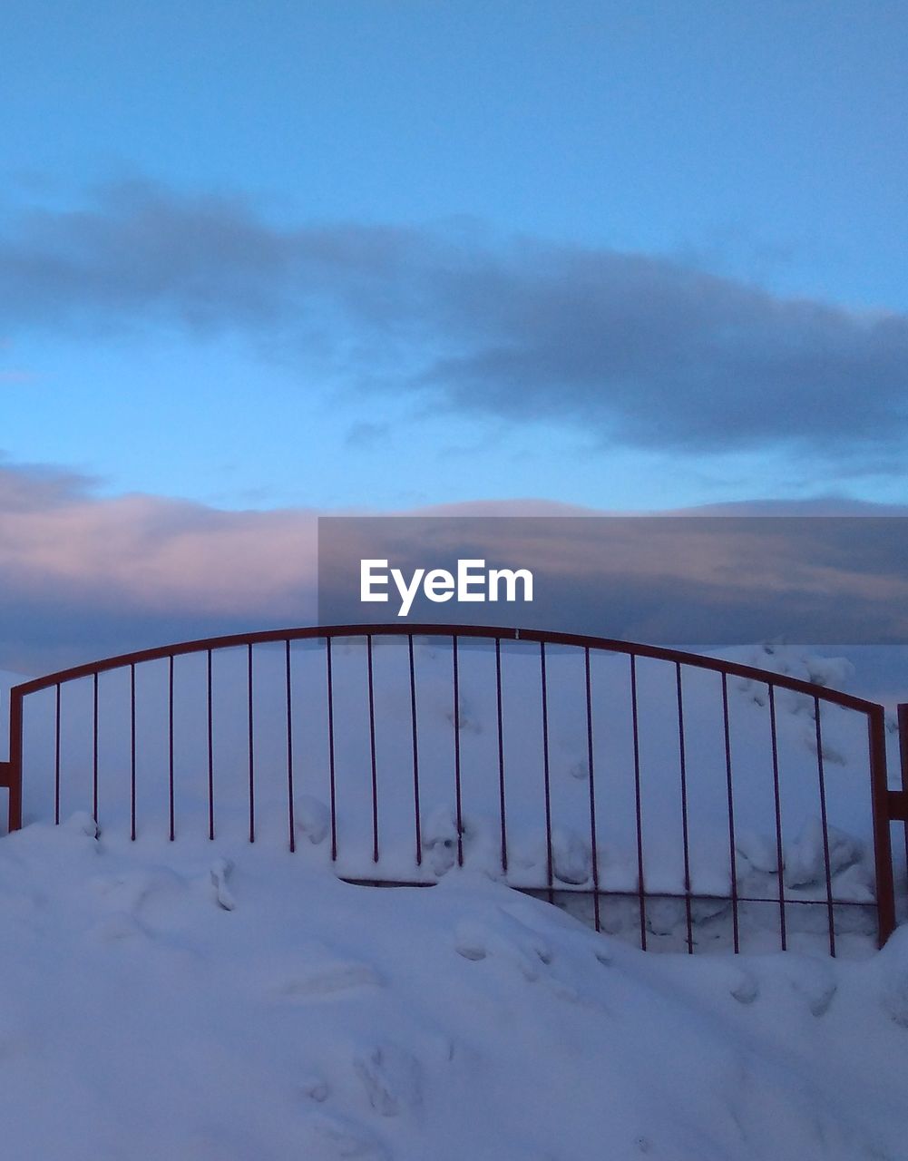 SNOW COVERED RAILING AGAINST SKY