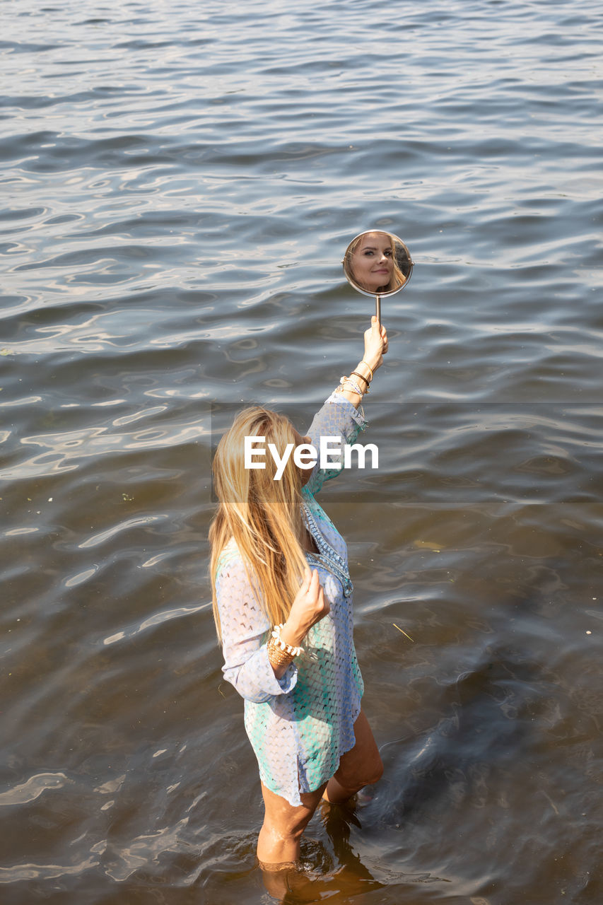 FULL LENGTH REAR VIEW OF WOMAN HOLDING SEA WATER