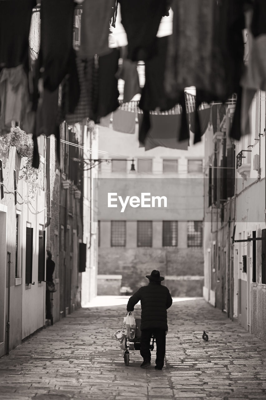 REAR VIEW OF TWO PEOPLE WALKING IN ALLEY