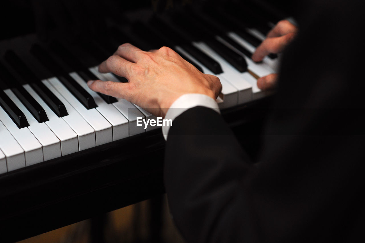 Cropped hands of man playing grand piano